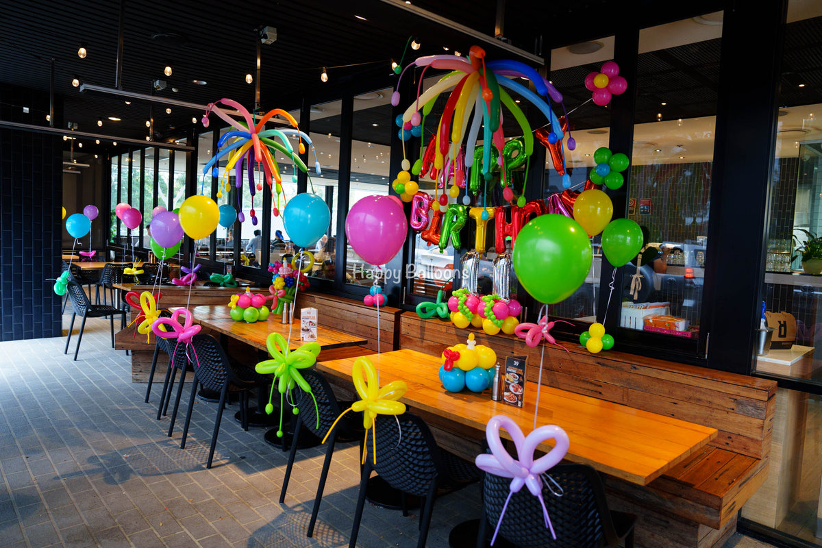 Colourful restaurant birthday styling with helium balloons, balloon flowers and ceiling firework details
