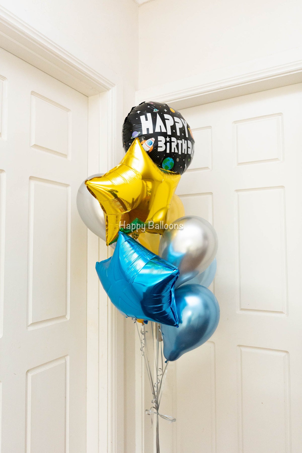 Blue, silver and gold helium balloon bouquet with foil stars and a Happy Birthday balloon photographed by Happy Balloons