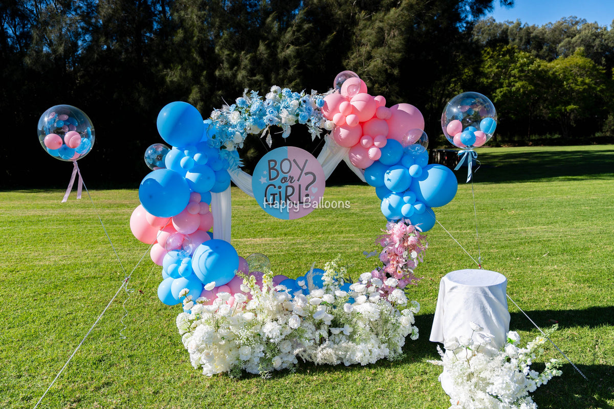 Outdoor pink-and-blue circular balloon ring with artificial flowers and guy lines at Olympic Park