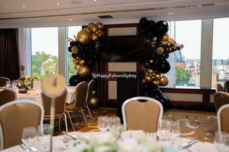 Black-and-gold balloon garland and floral table styling in a Shangri-La Hotel Sydney event room