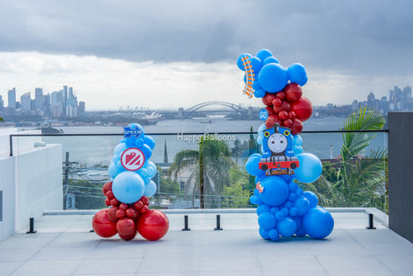Outdoor red-and-blue balloon columns overlooking Sydney Harbour in Vaucluse