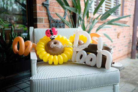 Oh Baby balloon lettering with sunflower and ladybug details at a baby shower