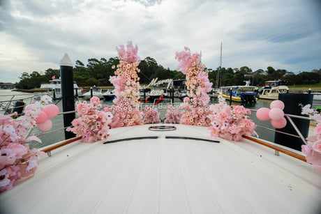 Pink floral proposal installation with a Marry Me LED sign on a yacht bow